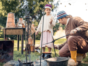 A man and a child enjoy cooking over an open fire.