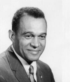 A black and white photo of a man in a suit and tie, representing black history.