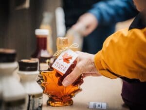 A person is holding a bottle of maple syrup.