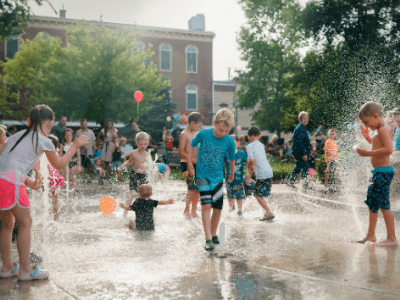 A group of children enjoy playing in a water fountain, one of the many attractions in Oxford.