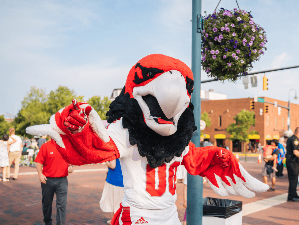 A mascot is standing on the street corner.