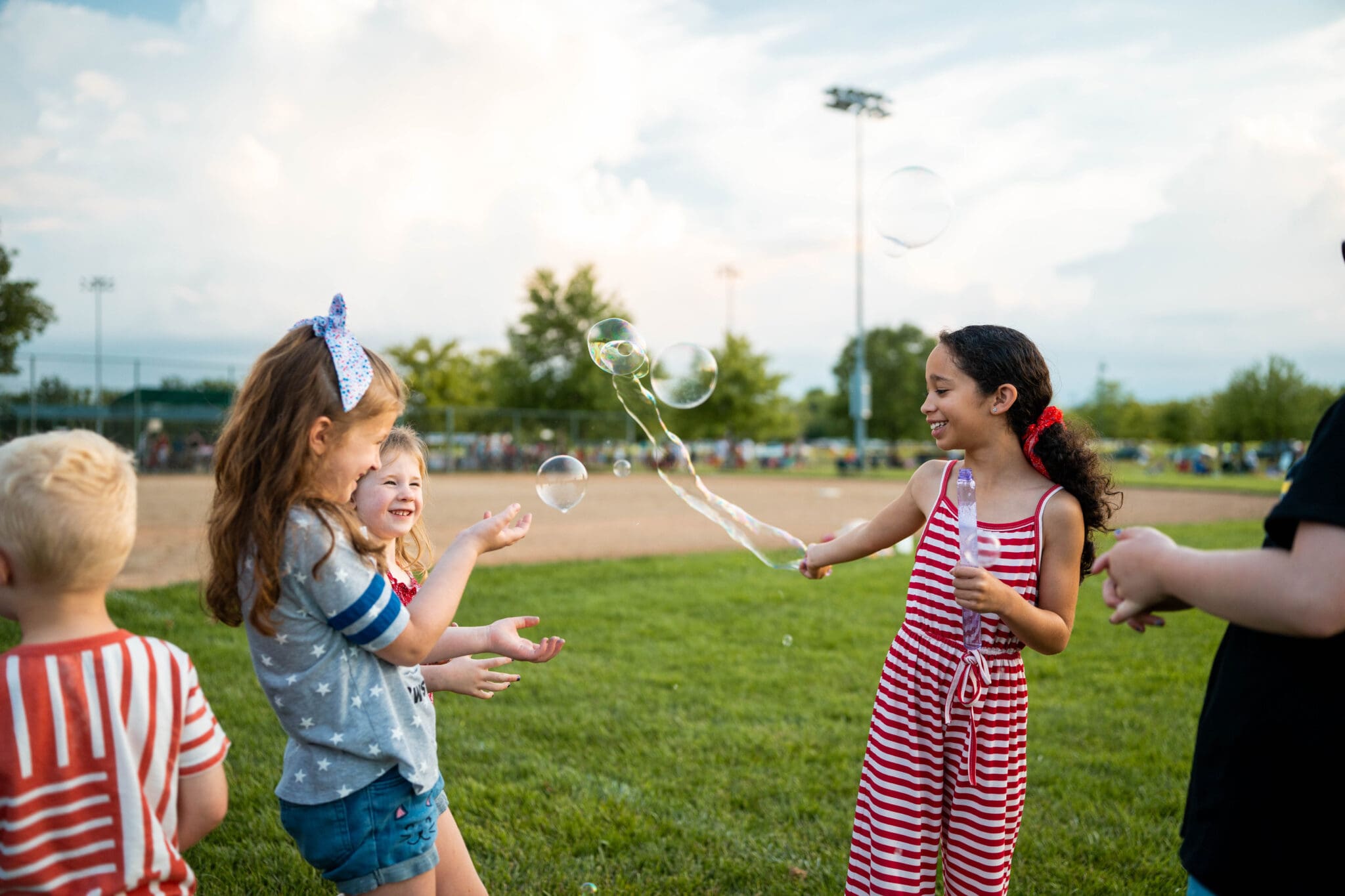 Children play with bubbles on a field.