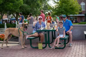 Photo of a family eating at the picnic tables with their dog