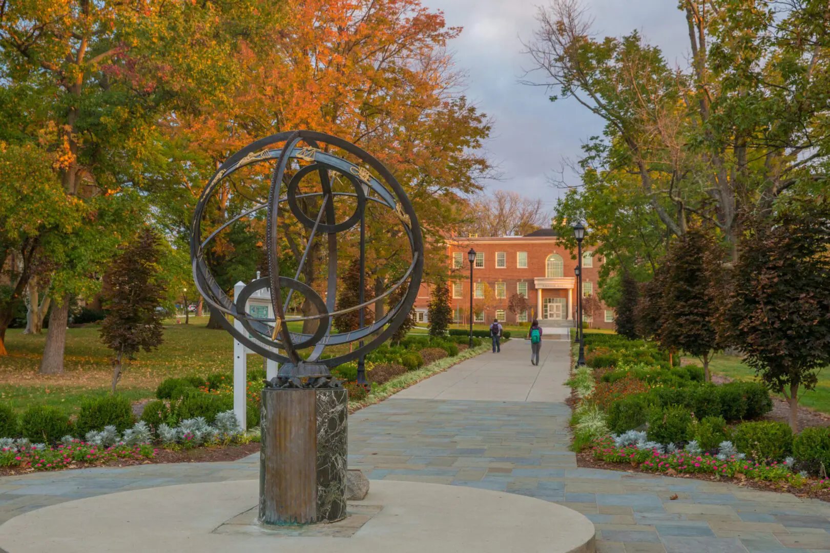A statue of an armillary sphere in the middle of a park.