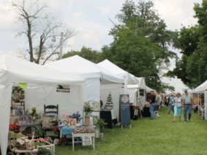 A group of people browsing artist vendors on the lawn at the Hueston Woods Arts & Crafts Fair