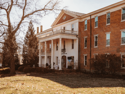 A large brick building with a porch and balcony.