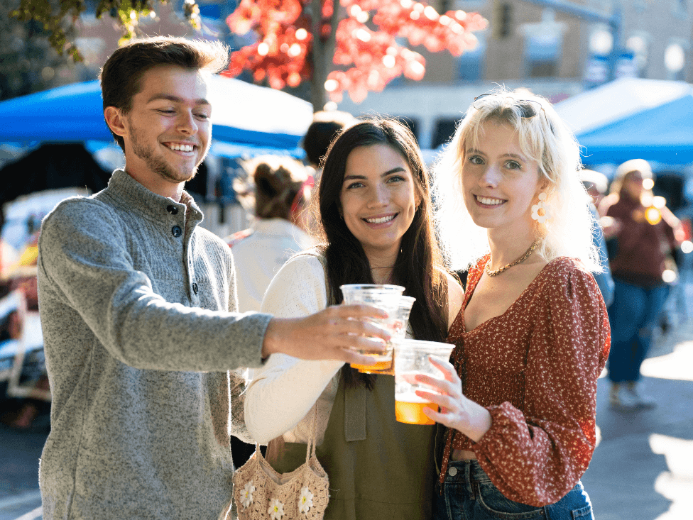 A group of people holding drinks at an outdoor event.