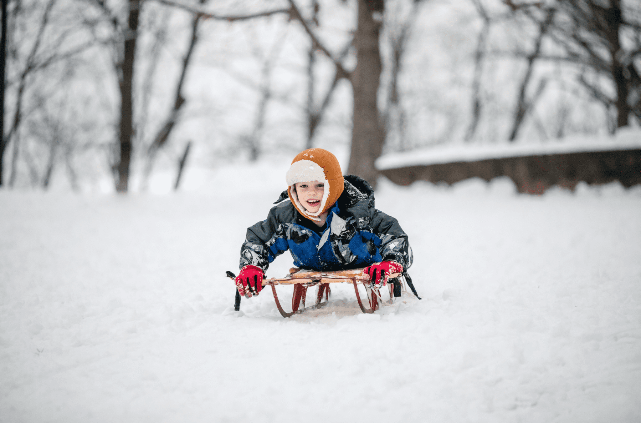 A child is riding down the hill on their sled.