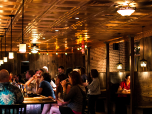 Interior of Oxford Pub with people drinking at the bar and inside wooden booths