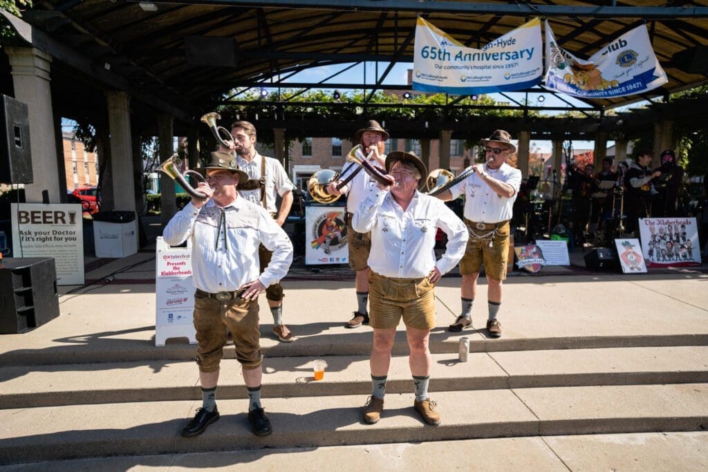 Group of men in traditional German leiderhosen blowing horns. 