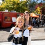 Two women holding drinks in front of a food truck.