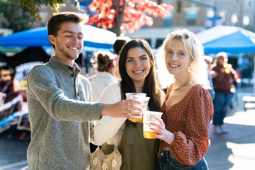 A group of people holding drinks at an outdoor event.