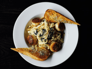 Sorriso food with a white plate topped with pasta and bread.