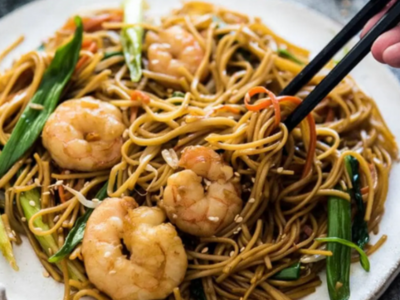A plate of noodles with shrimp and vegetables.