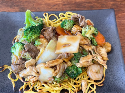 A plate of noodles with meat and vegetables.