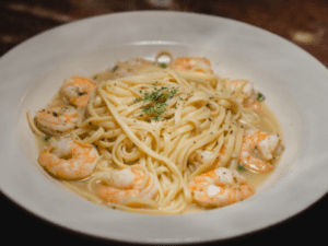 A plate of shrimp and pasta on top of a table.