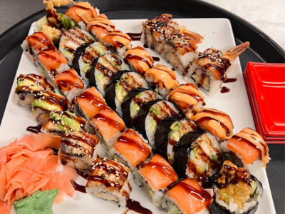 A plate of sushi with sauce and vegetables.