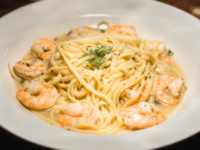 A plate of pasta with shrimp and sauce.
