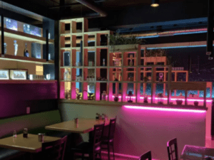 Inside MImian restaurant with tables and chairs around pink neon light.