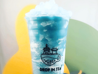 A blue drink with ice in it sitting on top of a table.