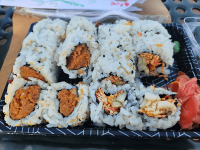A tray of sushi with sauce and rice.