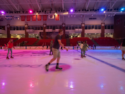 A group of people skating on an indoor rink.