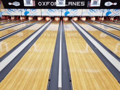 A bowling alley with lanes and a row of balls.