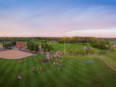 A group of people in the grass near some trees.