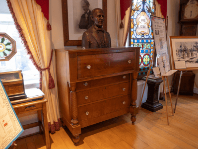 A wooden dresser with a bust of abraham lincoln on top.