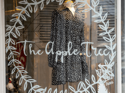 A black and white dress is in the window of an apple tree store.
