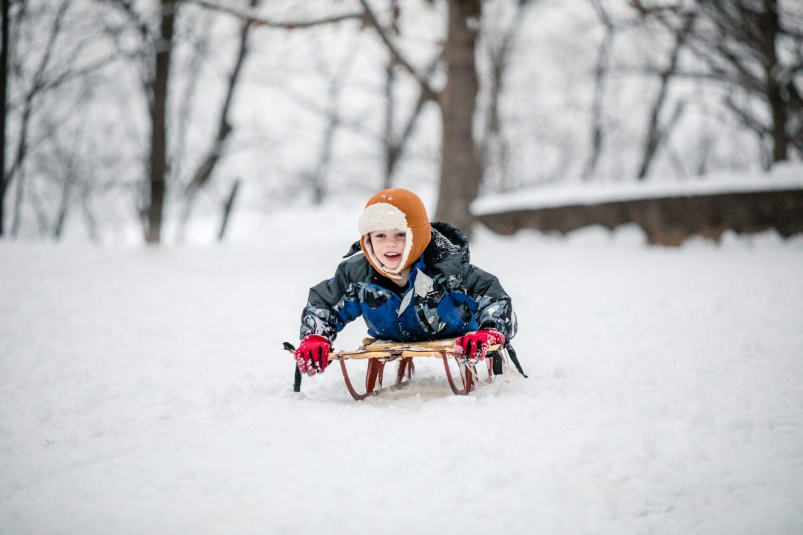 A child is riding down the hill on their snow board.