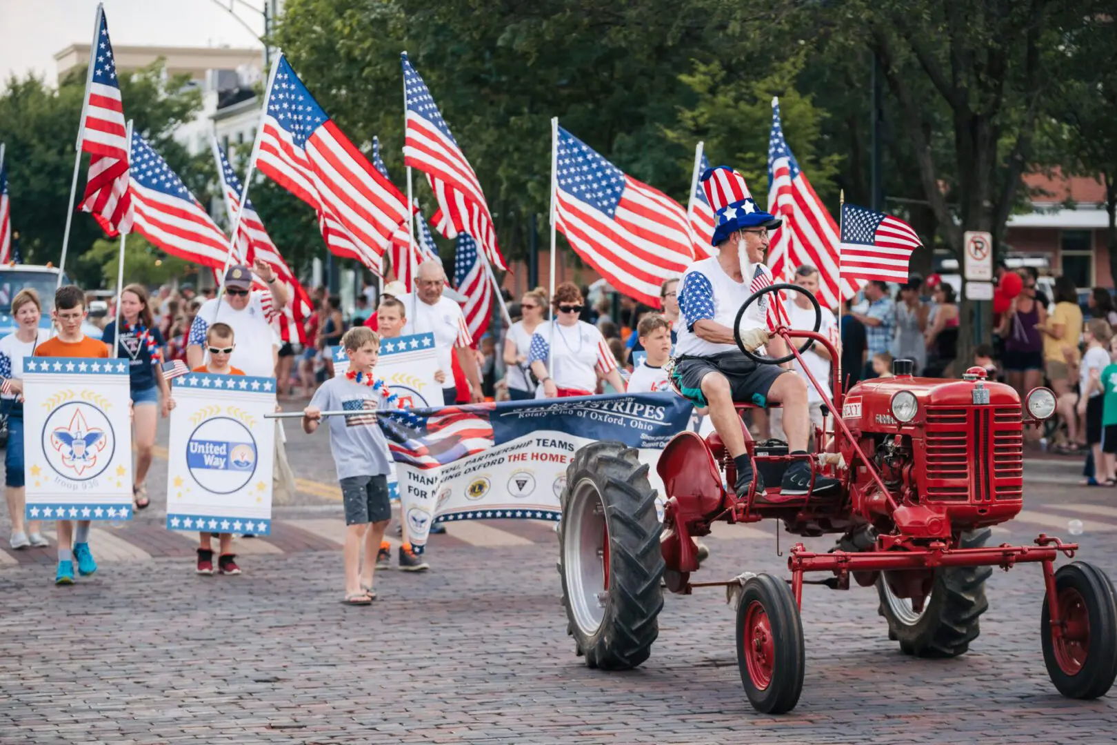 A group of people walking down the street with american flags.
