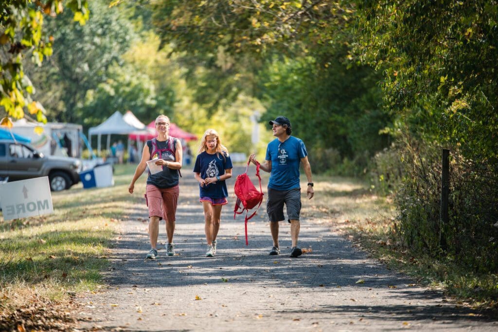 Two adults and a young girl walking along a hiking trail