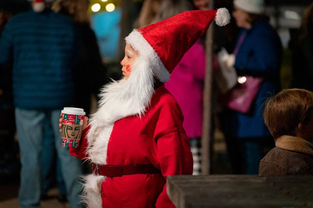 Little boy dressed as Santa holding a holiday cup