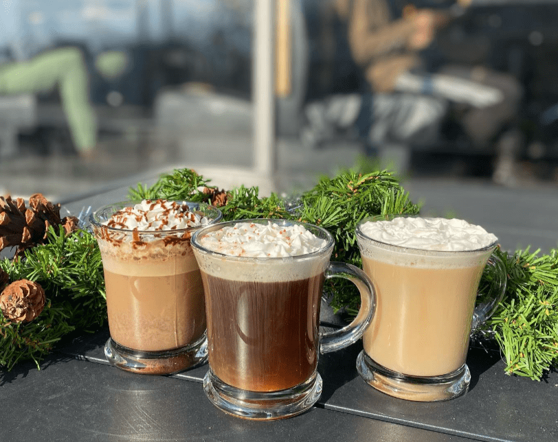 Three coffee drinks with whipped cream in clear mugs
