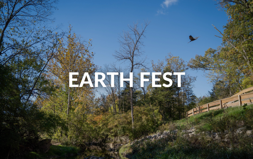 EARTH FEST text in front of a bird flying over a wooded trail