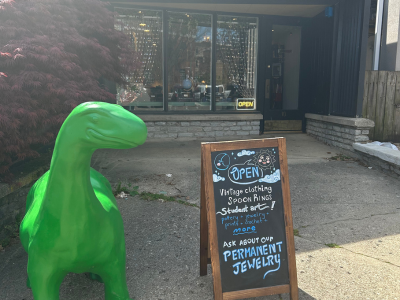 store front of College Artisans with a large green dinosaur