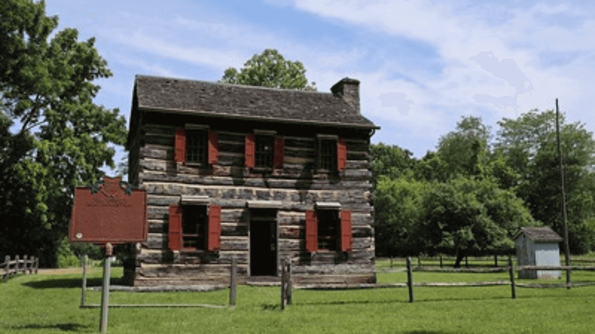 Historic log cabin with red shutters.