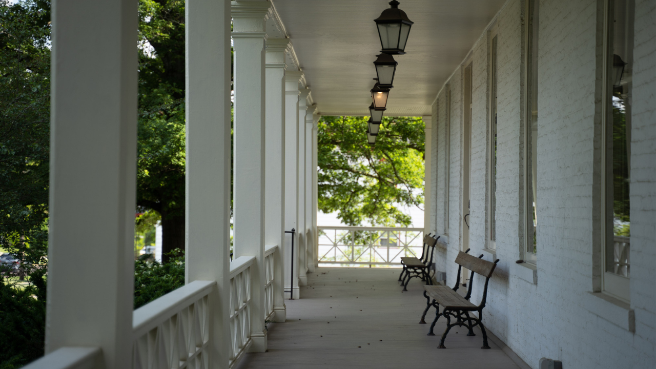 Covered porch of Oxford Community Arts Center with benches and gaslight lanterns on the ceiling