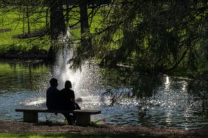 a couple sitting on a bench in a pond