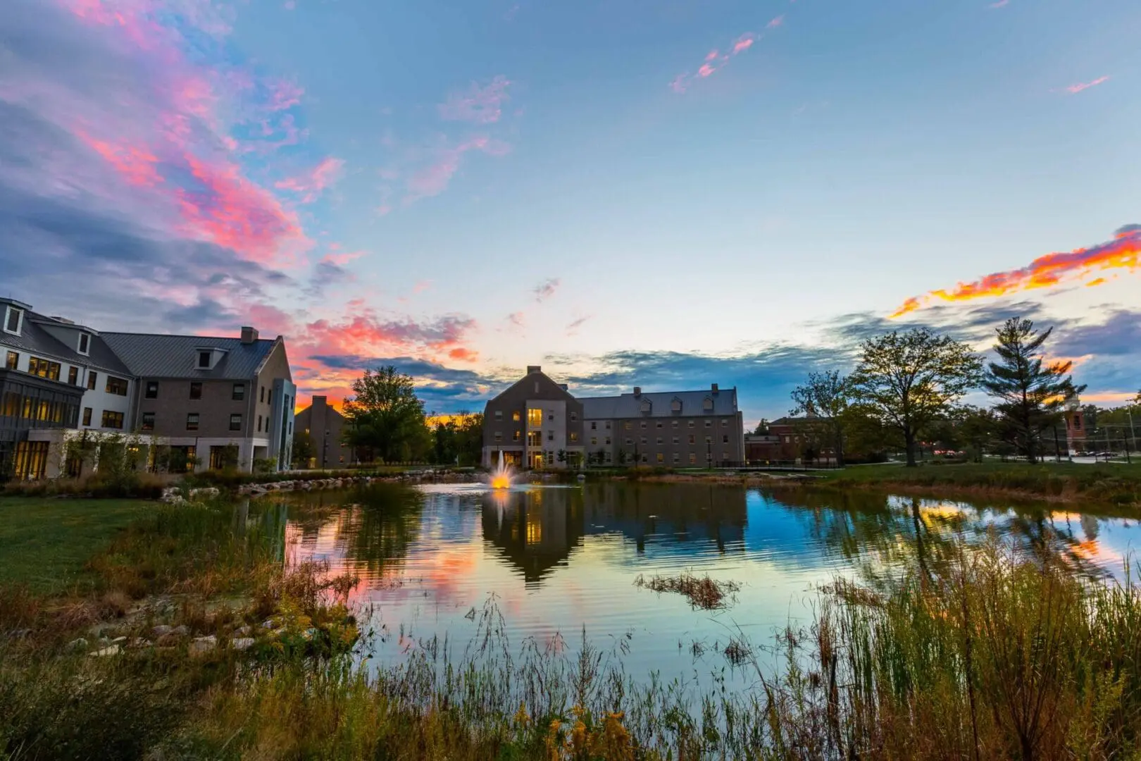 Sunset over a pond with buildings reflected.