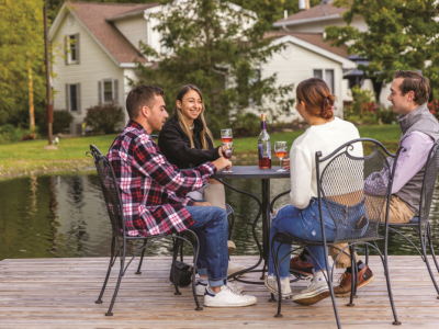 Young adults sitting outside by a pond enjoying a glass of wine