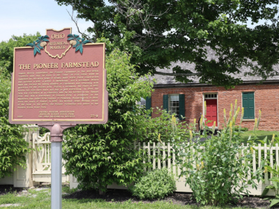 Doty pioneer homestead behind historical marker sign.