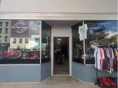 Exterior store front of Flow State Vintage shop with a rack of clothes for sale on the sidewalk.