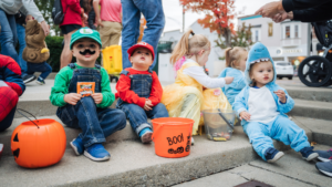 Kids in costume sitting on the pavilion steps with their treats.