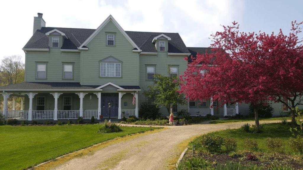 Landscape photo of the White Garden Inn with green siding and wrap around porch