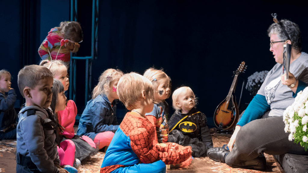 a group of kids in costumes listening to a book reading