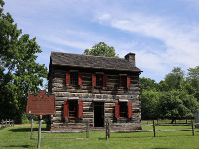 Front view of DeWitt log cabin with historical marker