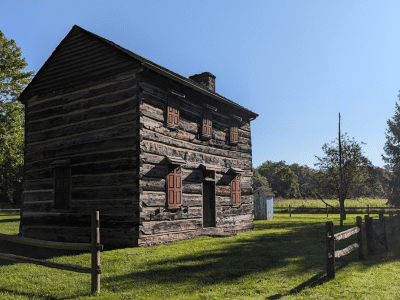 Historic log cabin on sunny day.