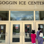 Two people walking into the Goggin Ice Center